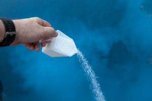 Pouring liquid chlorine into swimming pool as part of a regular maintenance.